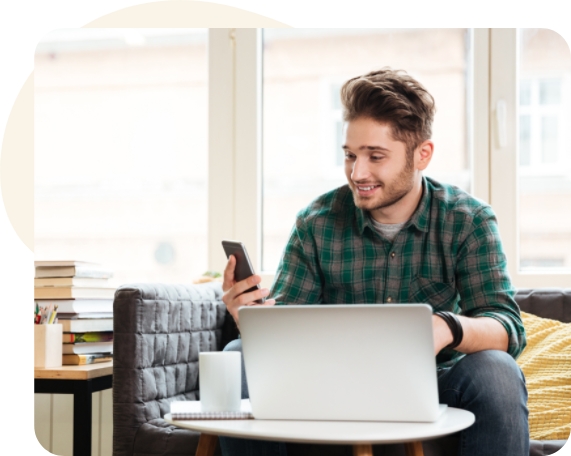 Homme devant un ordinateur portable et vérifiant le téléphone